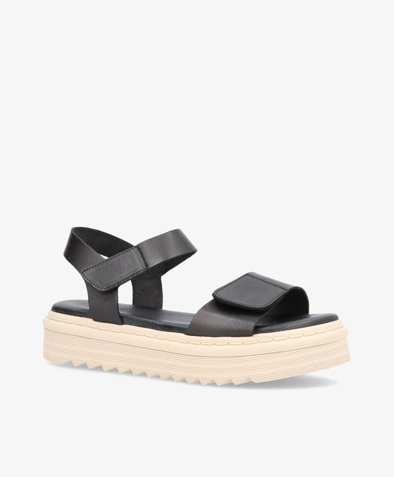 Sort sandal med tyk, hvid sål og justerbare stropper.
