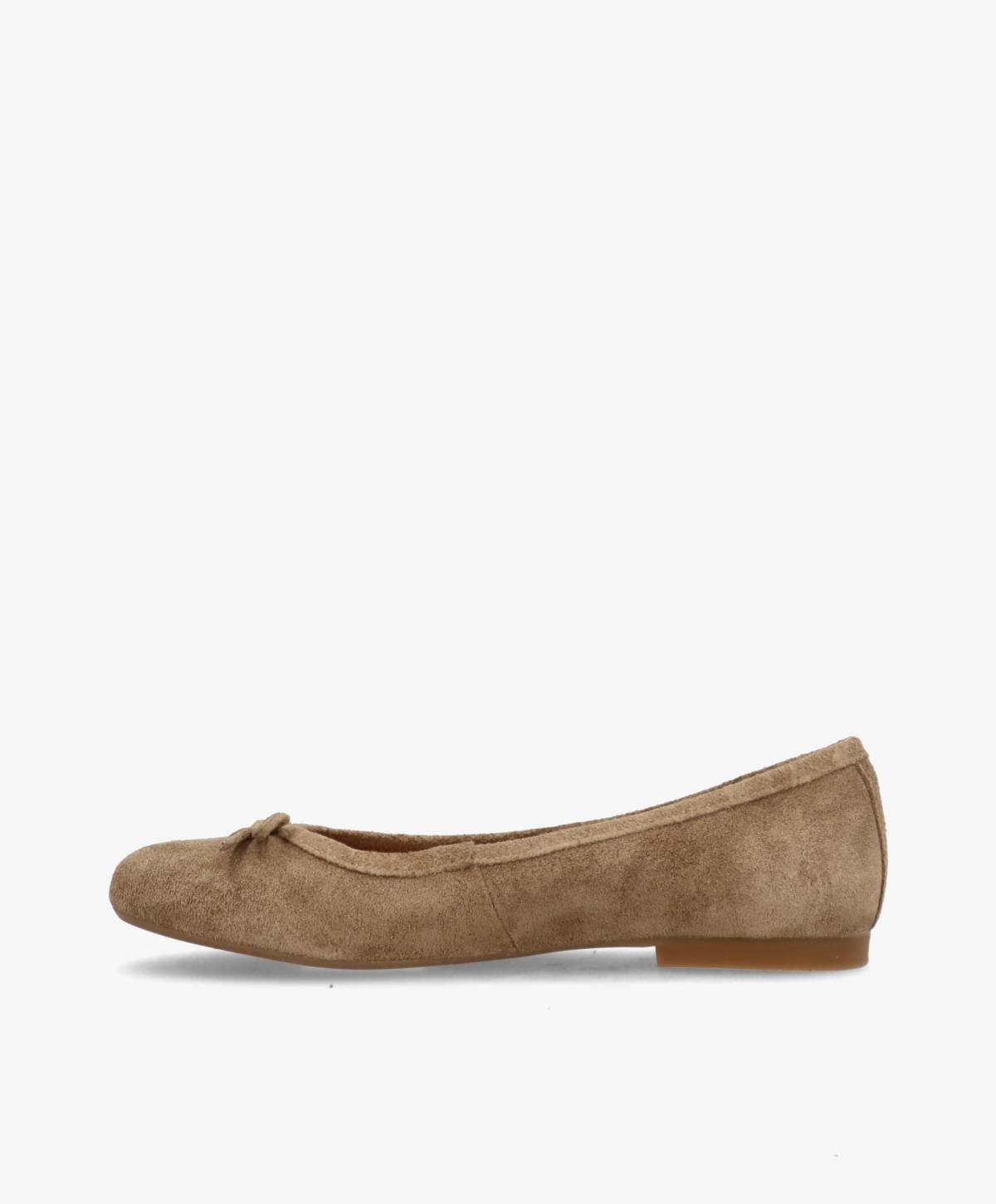 Beige ballerina-sko i ruskind med en lille sløjfe på snuden, set fra siden.