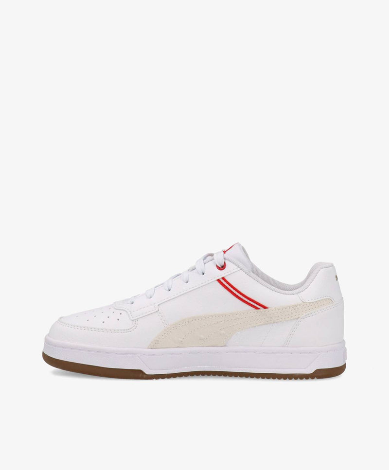 Hvid sneaker med røde detaljer og brun sål, set fra siden.