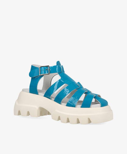 Blå sandal med tyk, hvid sål og justerbar rem.
