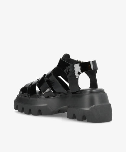 Sort sandal med tyk, rillet sål og flere remme i blankt materiale.