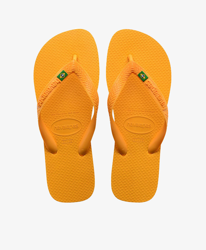 Gule Havaianas slip-ins med logo og brasiliansk flag.