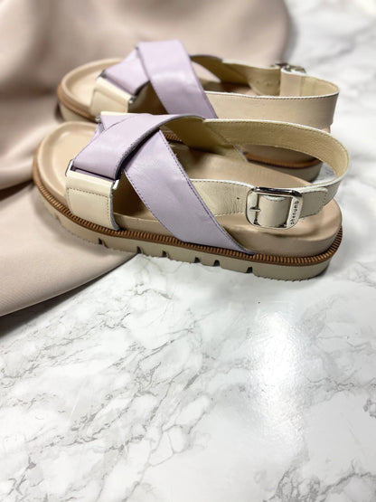 Beige og lilla sandaler med spænder på en marmoreret overflade.