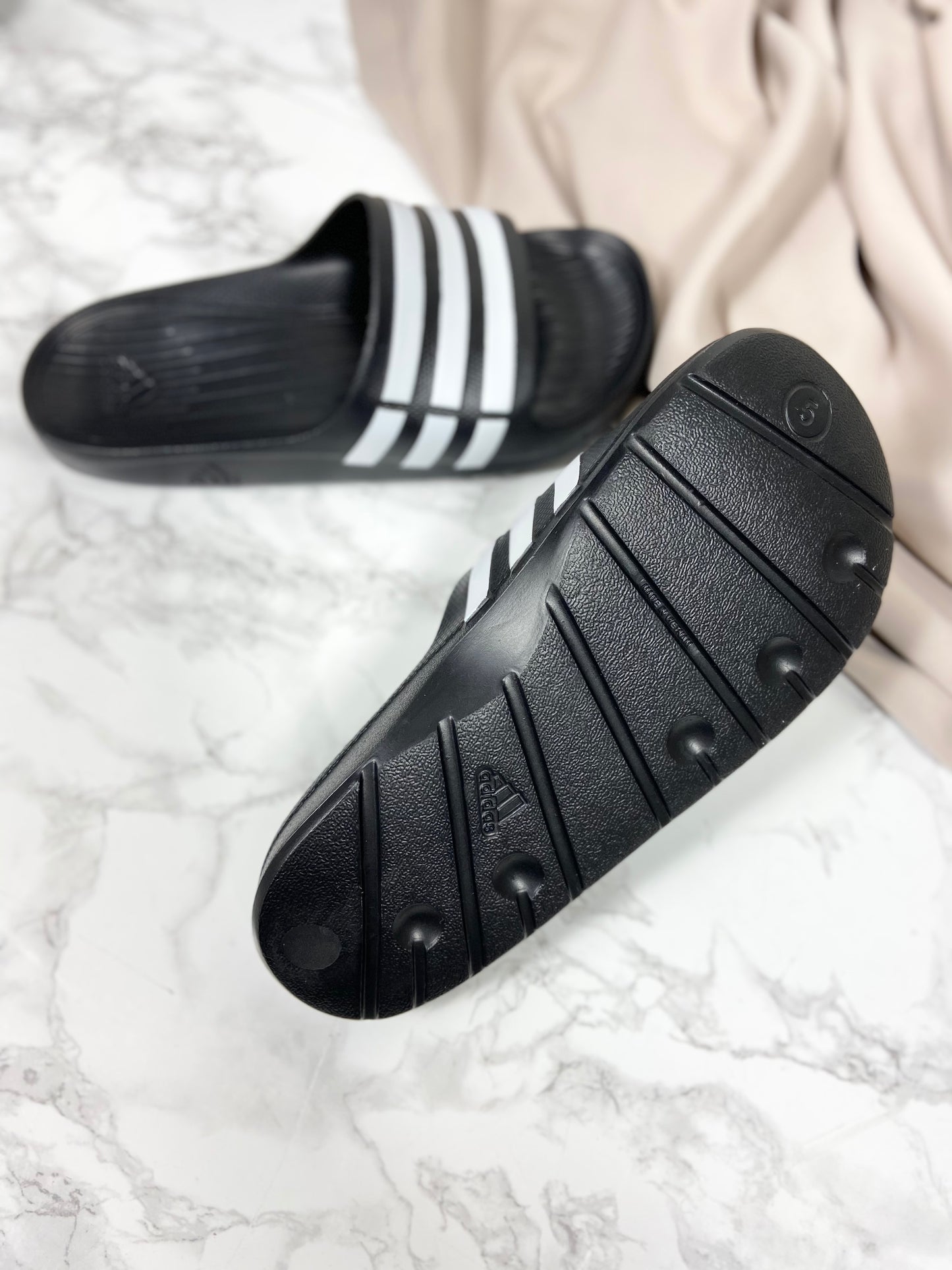 Adidas badesandaler med bred rem, hvorpå der er hvide striber.